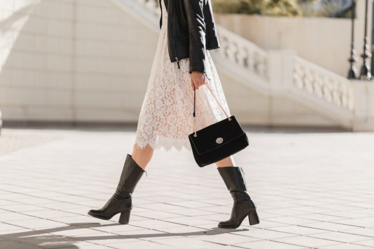 young pretty woman walking street fashionable outfit holding purse wearing black leather jacket white lace dress spring autumn style warm sunny weather romantic look 1